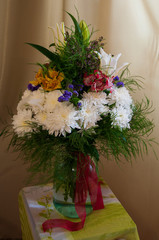 White lilyes, yellow and pink orchids, branch of lilac, chrysanthemums in the spring  tender bouquet on the background with green curtain