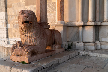 The stone lion statue at the entrance to a catholic church in Italy