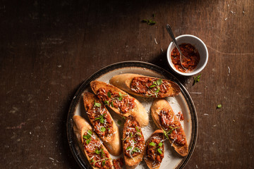 Italian bruschetta with olive paste, parmesan cheese and fresh oregano leaves. Rustick, wooden background.