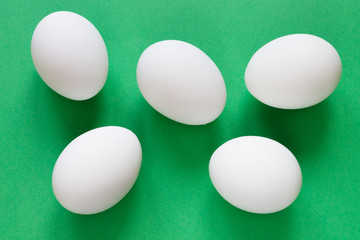 Five white eggs lie on a luscious green background.