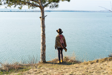 Yong hipster woman traveler in hat and poncho walking outdoors