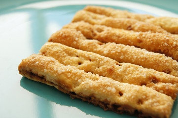 Delicious baked puff sticks with sugar and cinnamon on turquoise plate