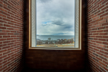 large window with brick interior, view of ocean and cloudy sky