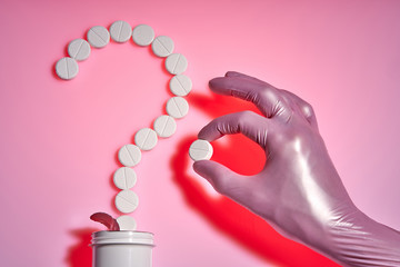 Question mark made from white pills on a pink background, flat lay with space for text. Doctor takes medicine in pink medical glove.