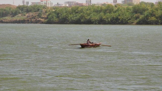 Man rowing a small fishing boat across the Nile River near Khartoum, Sudan
