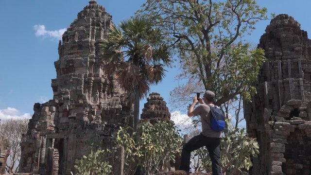Medium Exterior Shot of a Tourist Photographing an Ancient Temple Structure With Their Phone at Angkor Wat