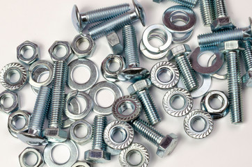 bolts and nuts in a heap on a white background