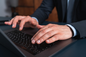 A man in suit typing the contract on laptop. The concept of entering into legal power to take liabilities. Formal wearing.