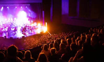 Fotobehang Lights on stage during concert in hall filled with spectators © leszekglasner