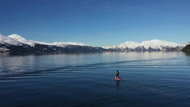 Fly by drone shot of a paddle boarder out exploring on Prince William Sound, Alaska.