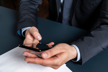 A businessman in suit typing on smartphone. Formal wearing.