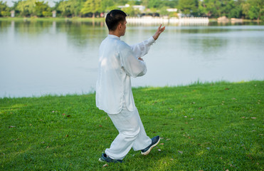 Young man practicing traditional Tai Chi Chuan, Tai Ji and Qi gong in the park for healthy,...