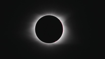 Telephoto tracking shot of total solar eclipse as it begins to flare. - Powered by Adobe