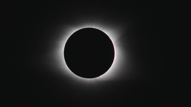 Telephoto tracking shot of total solar eclipse as it begins to flare.