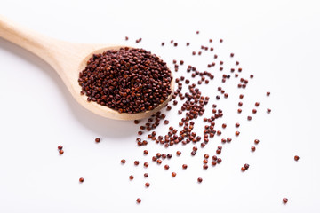 Red quinoa in wooden spoon on white background