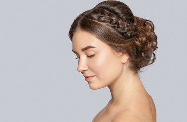 Portrait of a beautiful happy woman with beautiful fresh make-up and with clean skin, with a wedding hairstyle in a beauty salon. The hairdresser does the hairstyle. Wedding hairstyle.