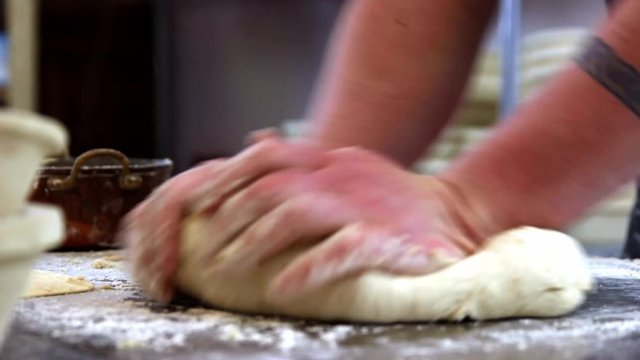 baker kneading bread dough roughly, close