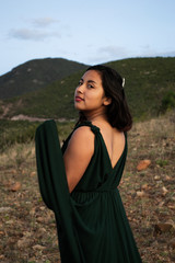 mujer joven hermosa y alegre con vestido verde en medio de la naturaleza