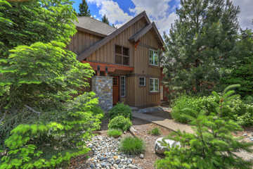Fototapeta na wymiar Cedar brown mountain home with great landscaping and rocks, modern lines of the front exterior.