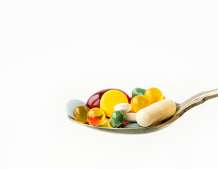 Assorted pharmaceutical medicine pills, tablets and capsules in a spoon on white background. Healthcare concept.