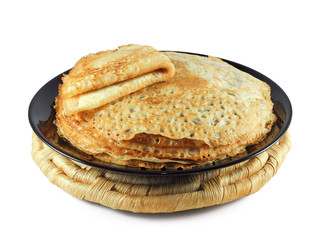 Porous homemade crepes (thin pancakes) on black plate and straw mat isolated on white background....