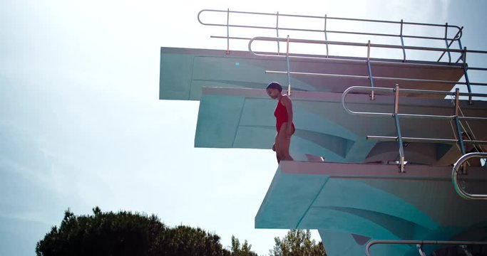 Slow motion shot of female swimmer on diving tower