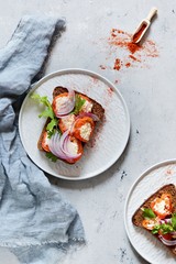 Sandwich with baked pepper stuffed cream cheese, arugula, smoked paprika and blue onion on a blue background. Italian bruschetta antipasti. Vegetarian food.