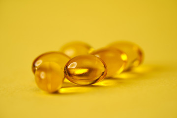 fish oil capsules on yellow background