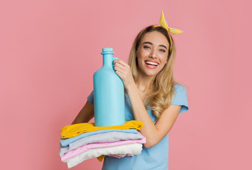 Smiling girl holds clean clothes and fabric softener