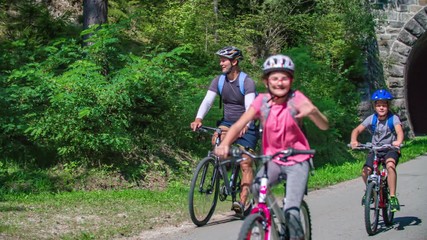 A happy family on bikes coming out from a dark tunnel in Strekna, a cycling path in Slovenia