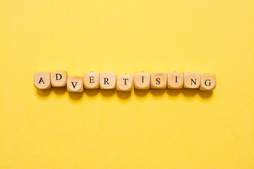 the word Advertising, text made with dice on yellow background