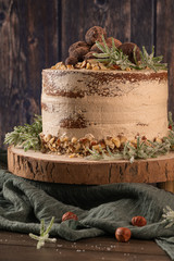 Delicious naked chocolate and hazelnuts cake on table rustic wood kitchen countertop.