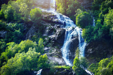 Panoramic beautiful deep forest waterfall in norway near blue ocean. Waterfalls mountain view close...