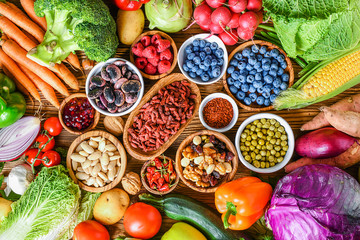 Healthy food eating variety selection in bowls: vegetables, fruits, berries, seeds, superfood, cereal, leaf vegetable on colorful background.