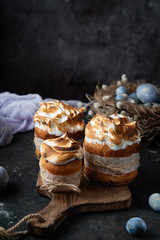 Easter cakes on an old wooden cutting board with colored eggs on a dark background