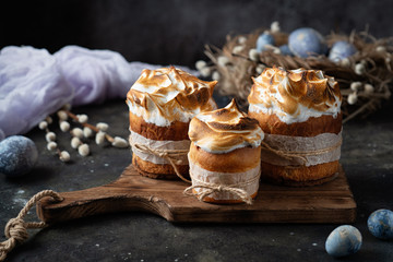 Easter cakes on an old wooden cutting board with colored eggs on a dark background