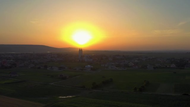 Moving aerial shot of a spiritual experience including a surreal sunset, church and small village