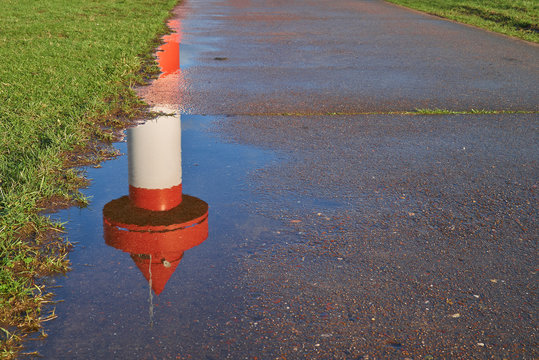 top of small lighthouse at Ritzenb&uuml;tteler Sand, municipality Lemwerder (district Wesermarsch, Germany) on a sunny spring day with blue sky reflecting in a puddle on a footpath