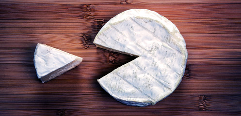 Beautiful, perfect, cut of tempting camembert cheese - in rustic style, with concepts of selecting, tasting, & enjoying cheese - added on a natural, rustic background.