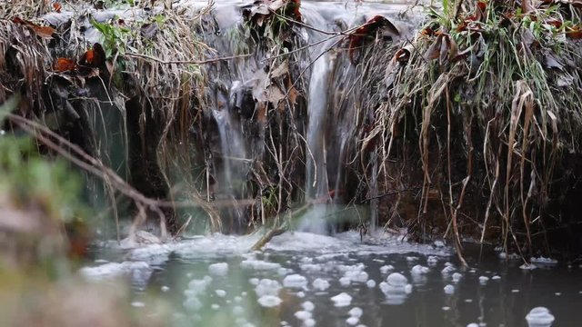 Stream of water flowing and bubbling in a creek full of water