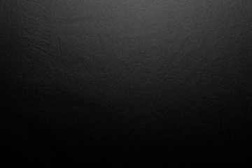 Black background made of real black paper with a matt fibrous structure, illuminated by a soft light from above. - obrazy, fototapety, plakaty