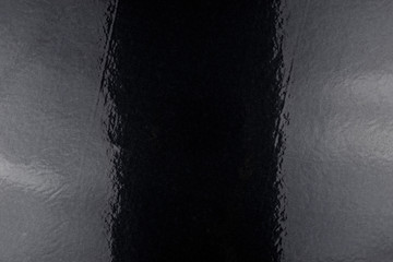 Black background made of real, shiny black paper covered with foil, illuminated by a soft light on...