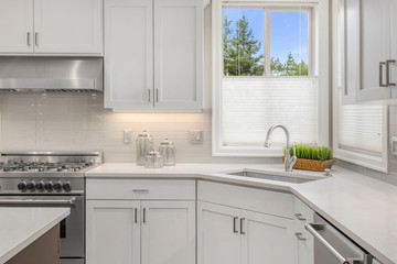Kitchen detail in new home. Features large sink and cabinets, with stainless steel oven, range, and...