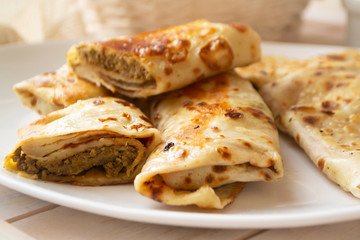 rolled delicious crepes with minced liver and meat pate on white plate, close up