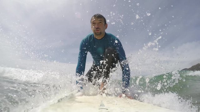 Slow motion of a surfer pop up seen from the surfboard