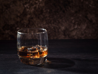 Whiskey splash in a glass with ice on a wooden table