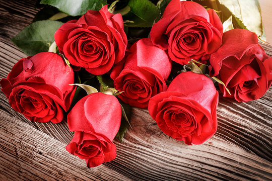 Red roses on old rustic table. Valentines day rose flowers.