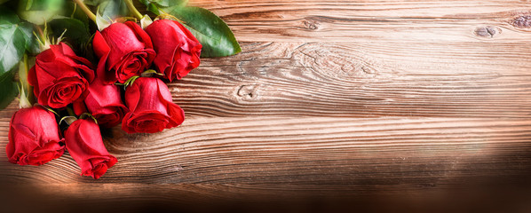 Red roses on vintage old wooden board.  Valentines day web wide rose banner