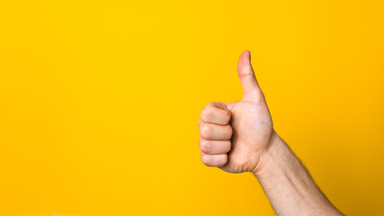 closeup hand with big thumb down over a wide yellow banner background with copyspace. dislike sign