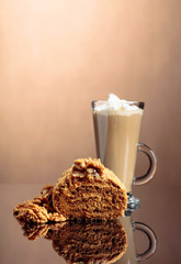 Walnut cake and coffee latte with cream on a reflective background.